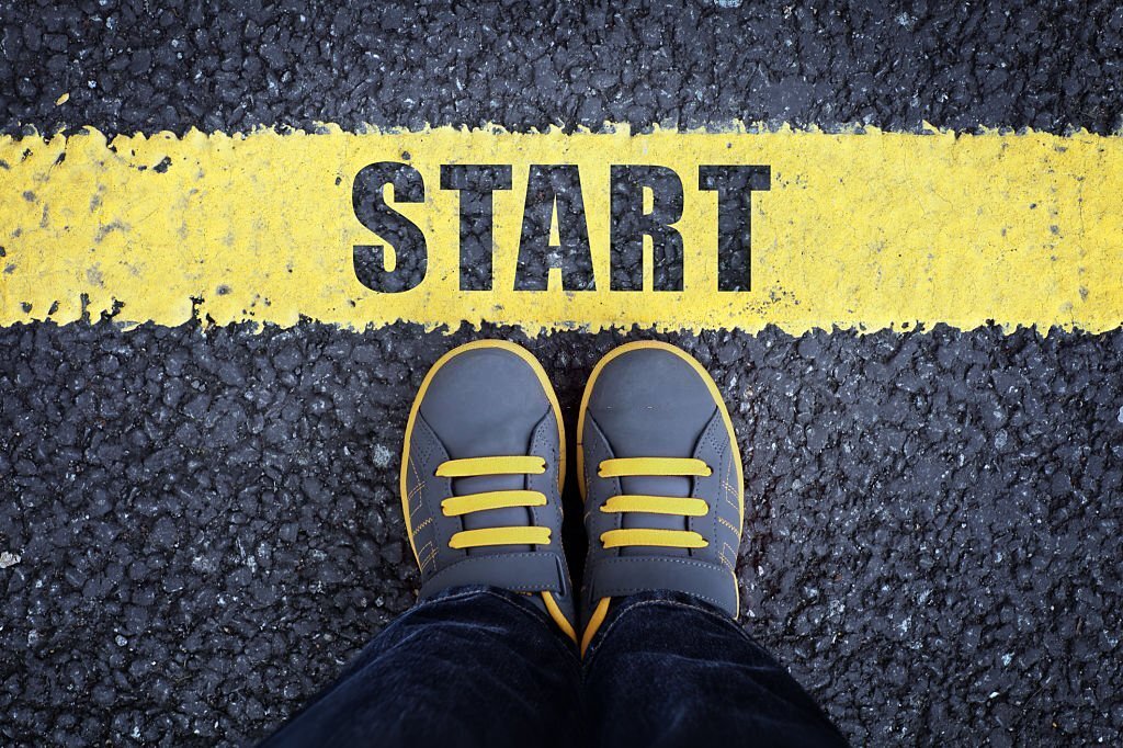 Start line child in sneakers standing next to a yellow starting line