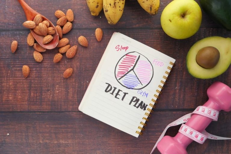 Diet plan with apple , almond, avocado and dumbbell on wooden background .