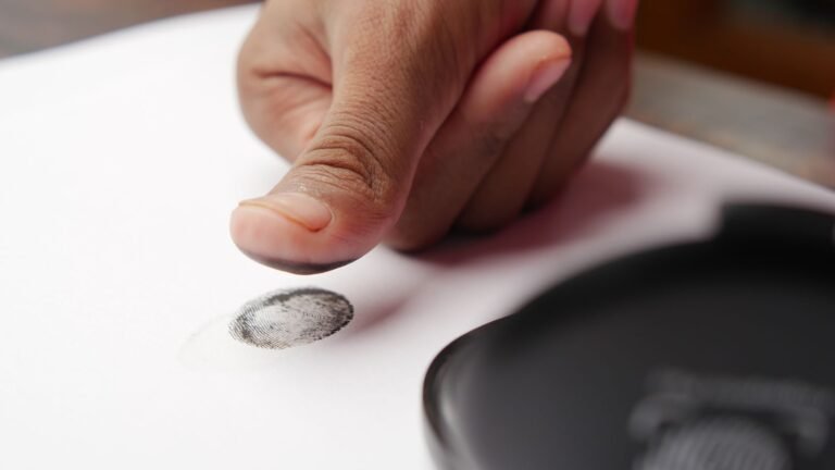 thumb leaving an ink fingerprint on paper, the kind of print fraudsters copy, which an Aadhaar biometric lock protects against