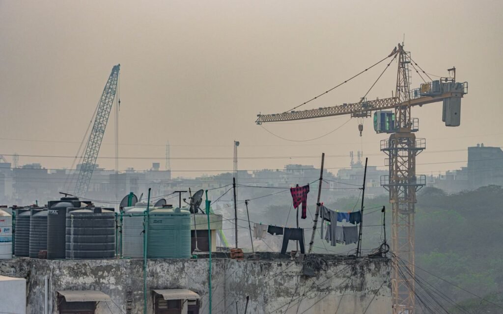 Rooftop water tanks and a construction crane under a hazy sky
