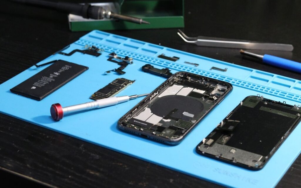 Opened iPhone, battery and parts laid out on a blue repair mat