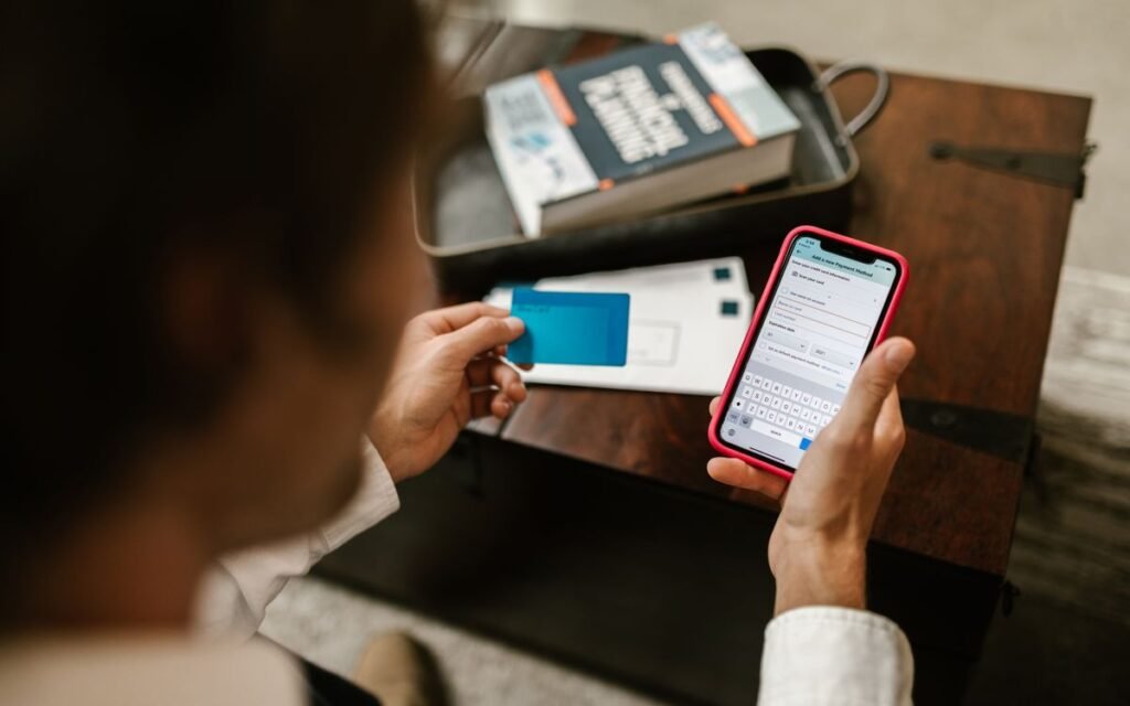 Hands holding a bank card and a phone showing an online form