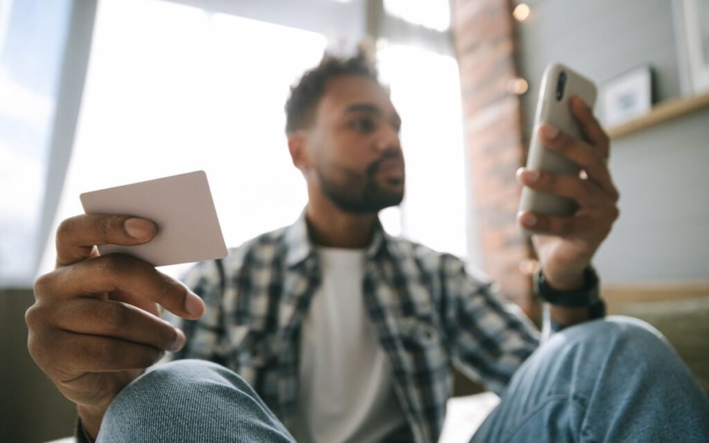 A man holding a bank card while looking at his phone