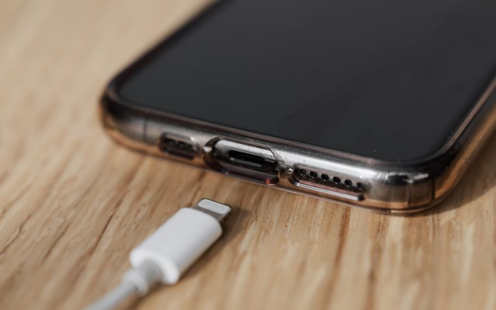 Close-up of a phone's charging port next to a white charging cable