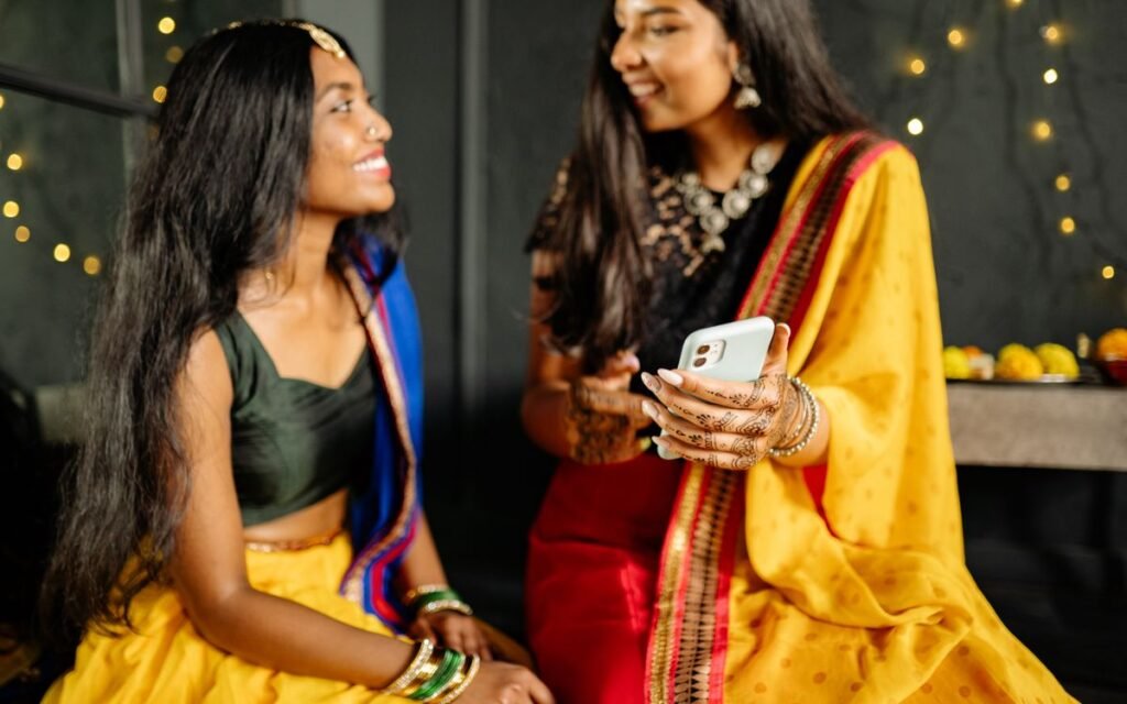 two women in festive saris looking at a phone