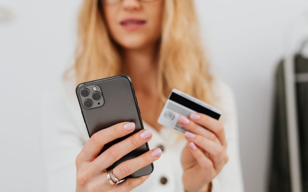 woman holding a smartphone in one hand and a bank card in the other