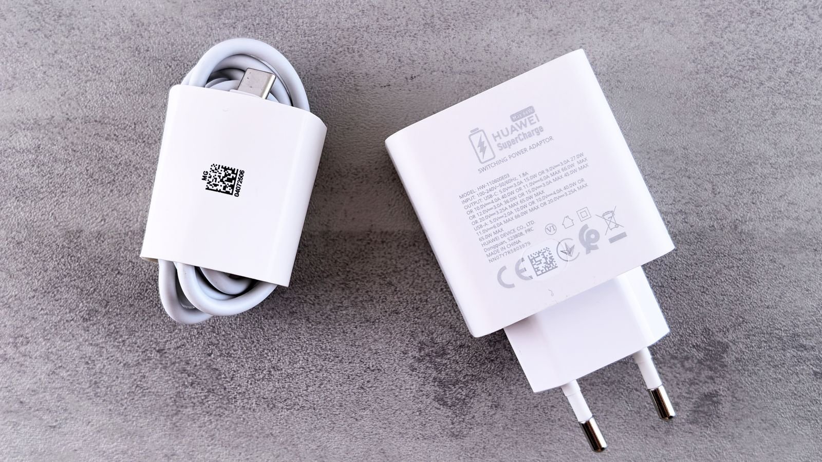 White charger with printed markings next to a coiled cable