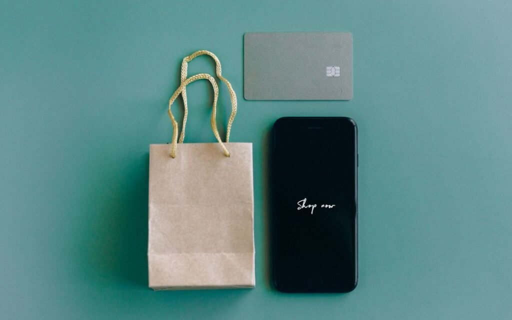 A paper shopping bag, a bank card and a smartphone on a table
