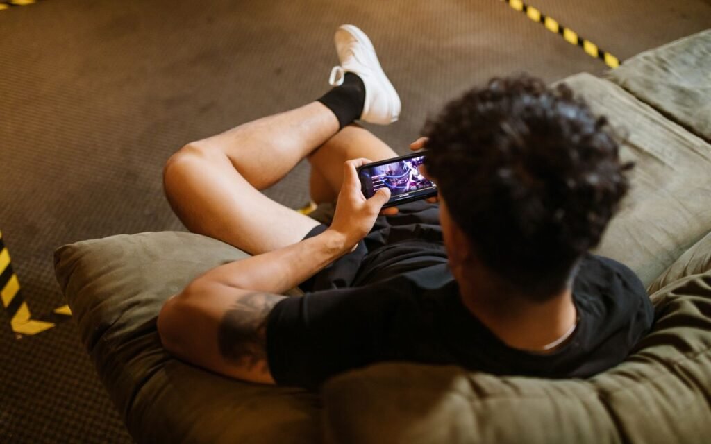 A young player lying back on a beanbag playing a game on his phone