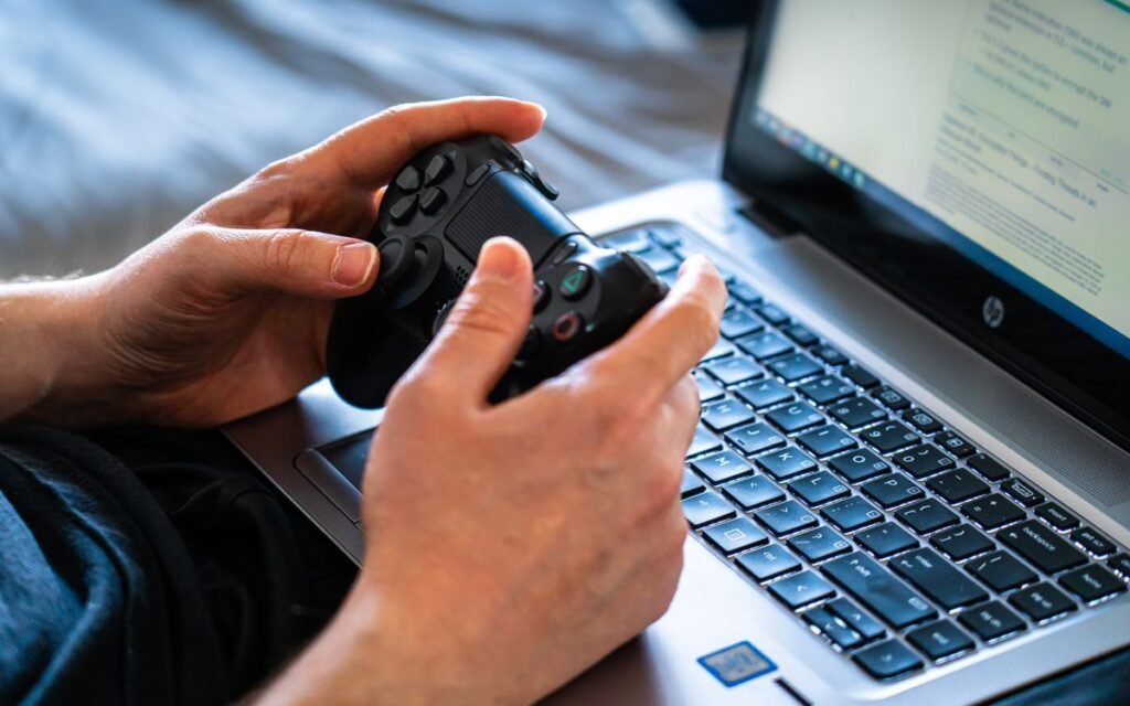 geforce now india: hands holding a controller over an office laptop