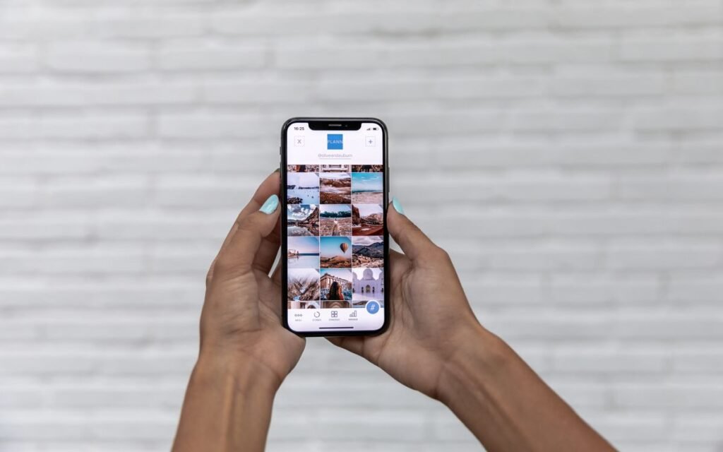 Two hands holding up a smartphone showing a photo gallery