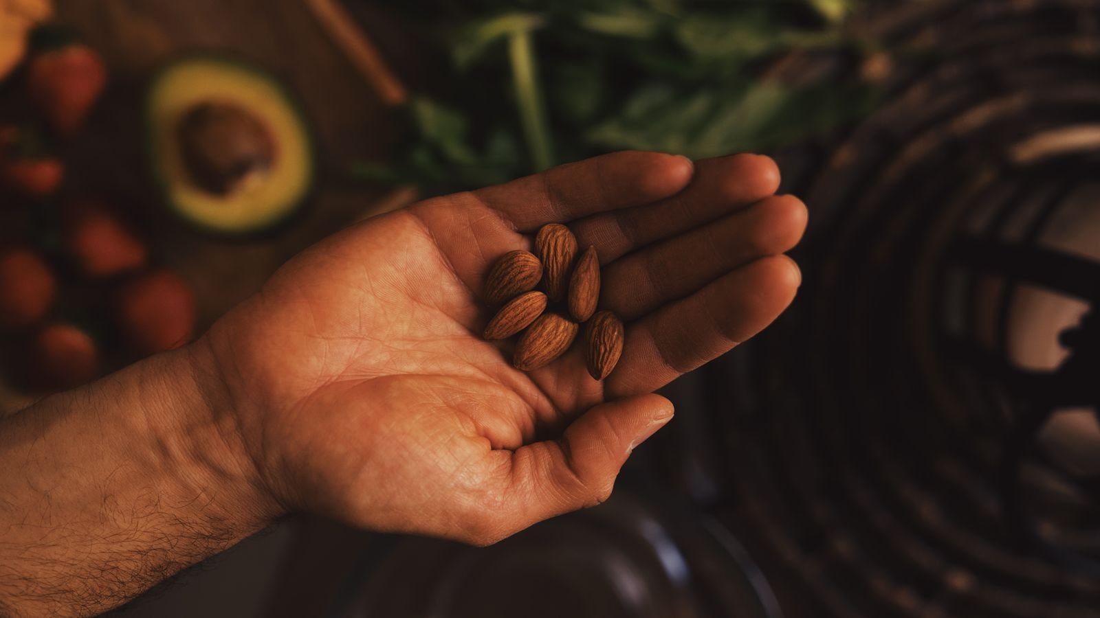 how many almonds a day: a hand holding a small handful of almonds