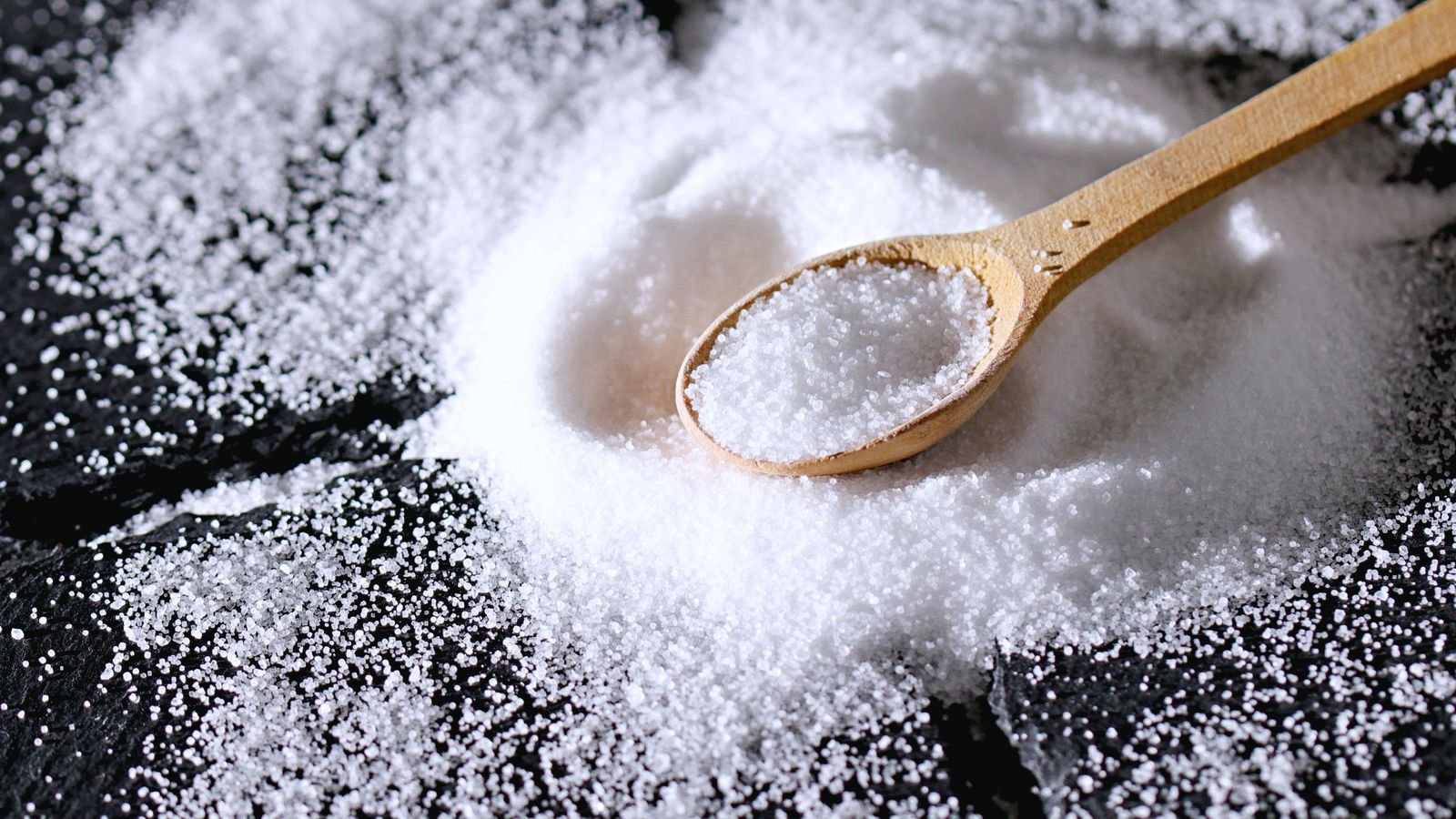 Wooden spoon resting in a heap of white salt