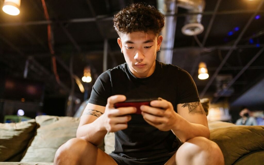Young man playing a mobile game on his phone at home