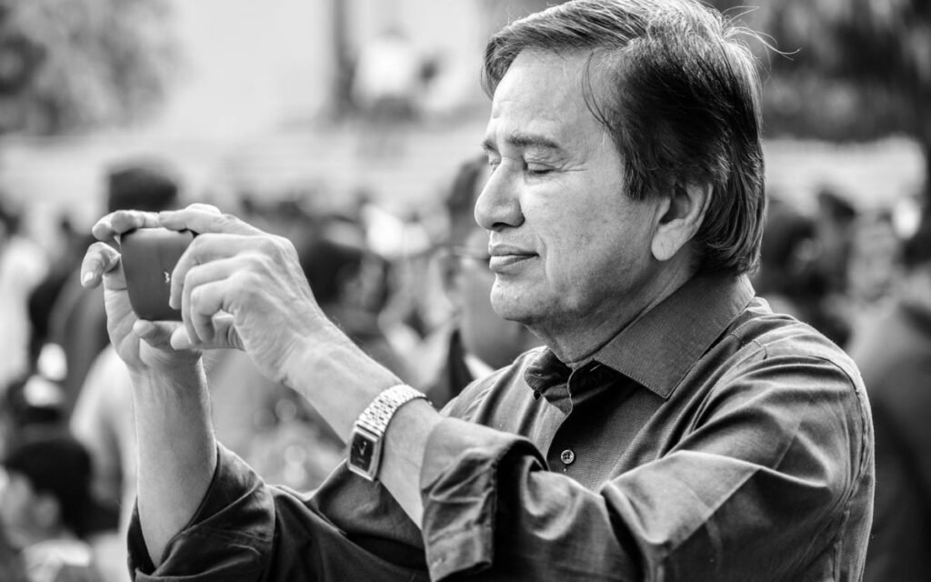 Older man holding up a smartphone to take a photo, black and white