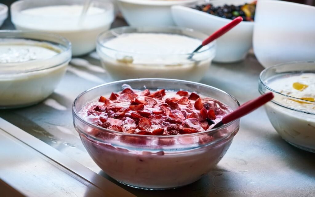 Bowls of curd, one topped with chopped strawberries