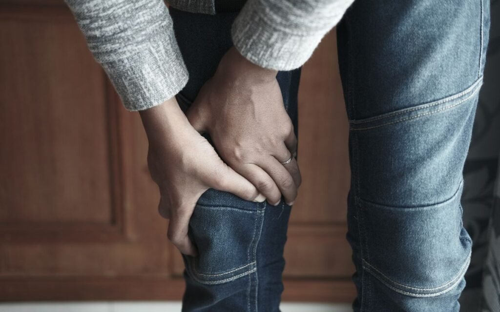 knee pain exercises: person in jeans holding a painful knee