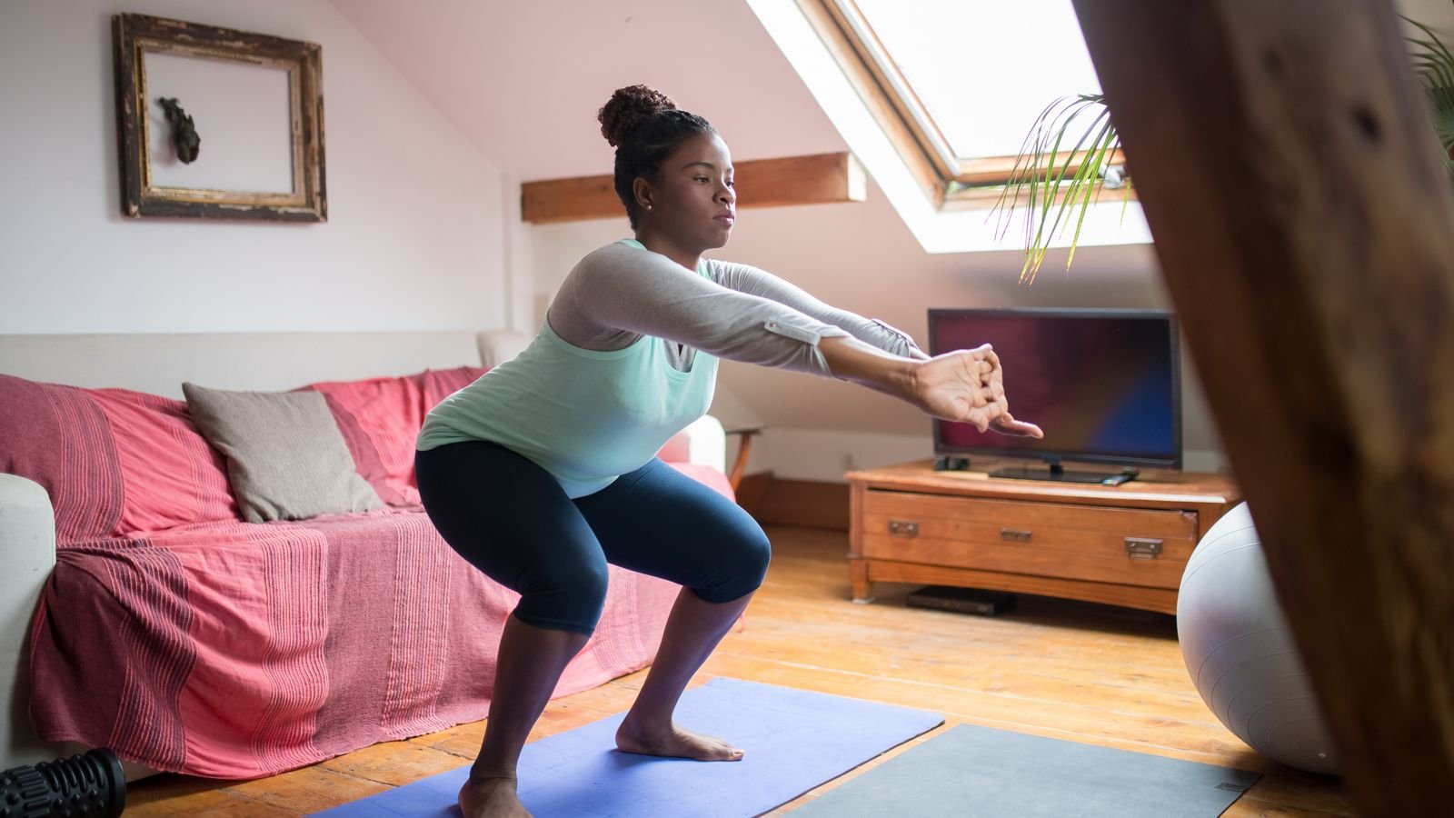 knee pain exercises: woman doing a squat in her living room