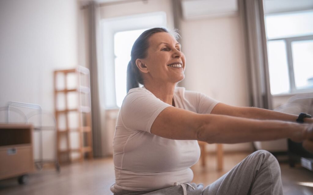 knee pain exercises: older woman doing a seated stretch at home