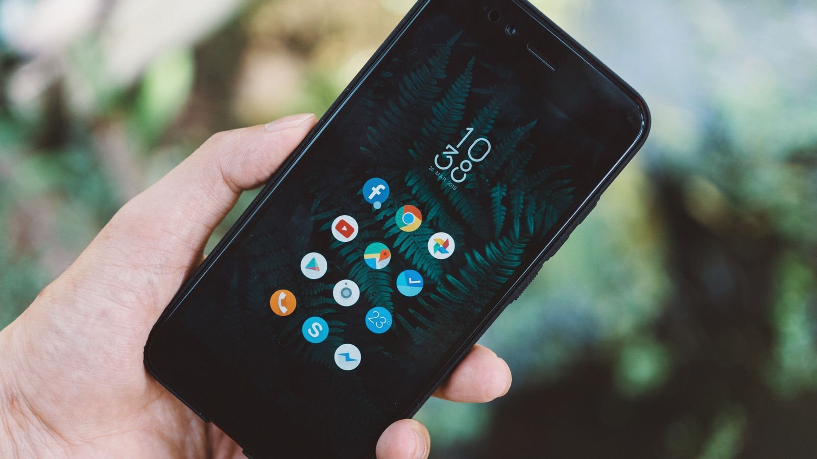 Hand holding an Android smartphone showing its home screen (representative image)