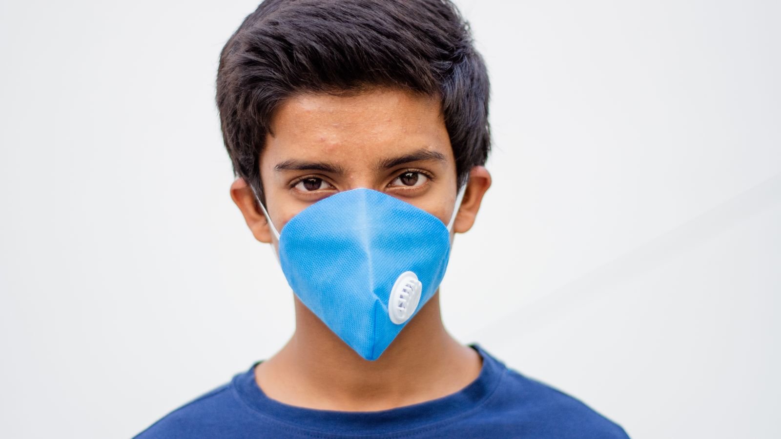 Teenager wearing a blue N95-style mask for pollution