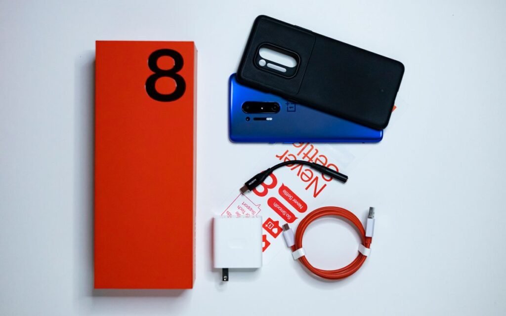 Phone box, two phones, charger and cable laid out on a white table