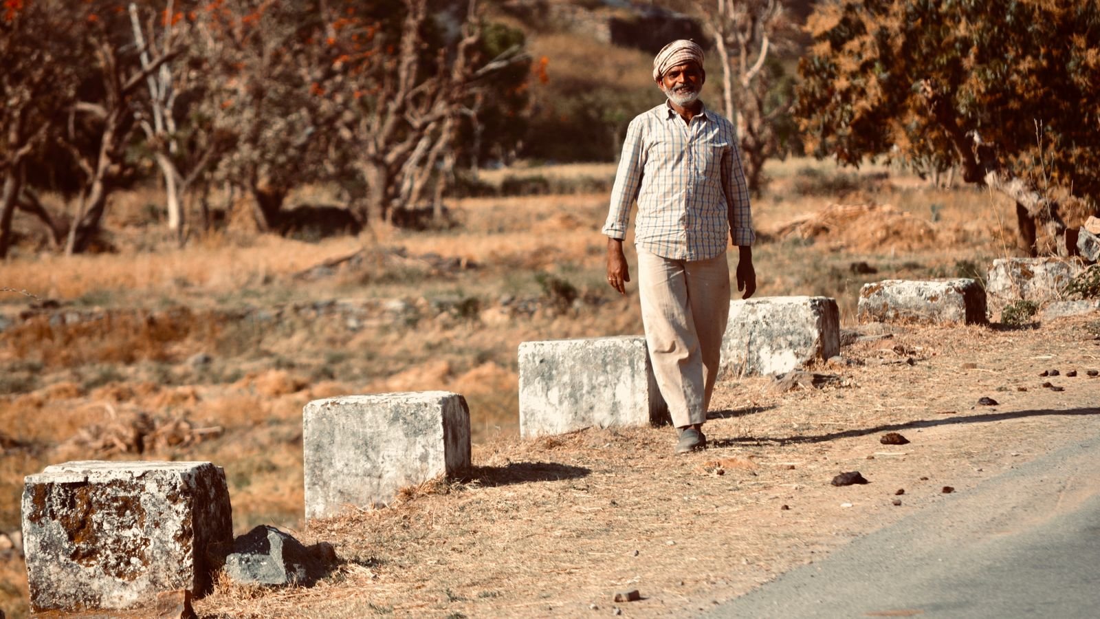 osteoporosis in men: older Indian man walking alone on a village road