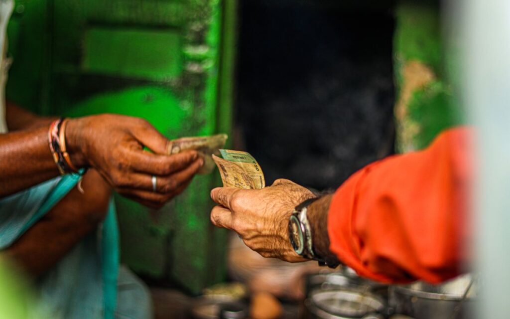Two hands passing cash notes to each other at a market stall