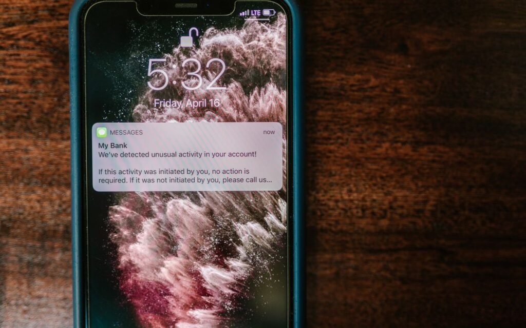 A phone on a wooden table showing a bank message about unusual account activity