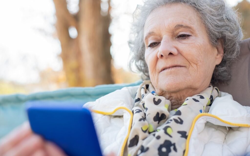 grey-haired older woman looking at her smartphone outdoors