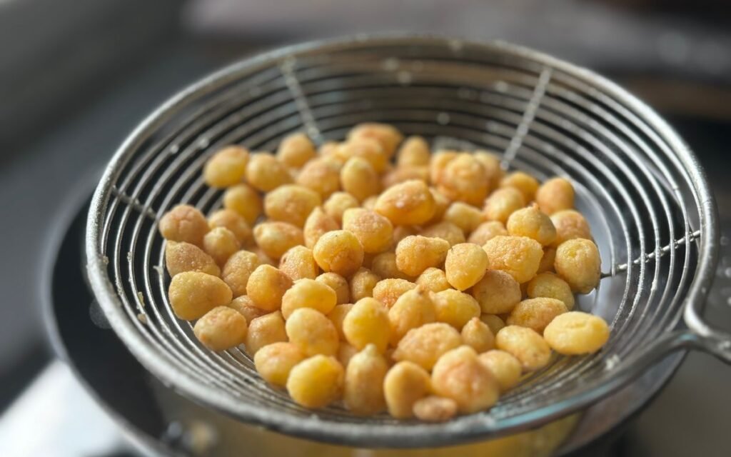 Golden fried snacks draining in a steel sieve