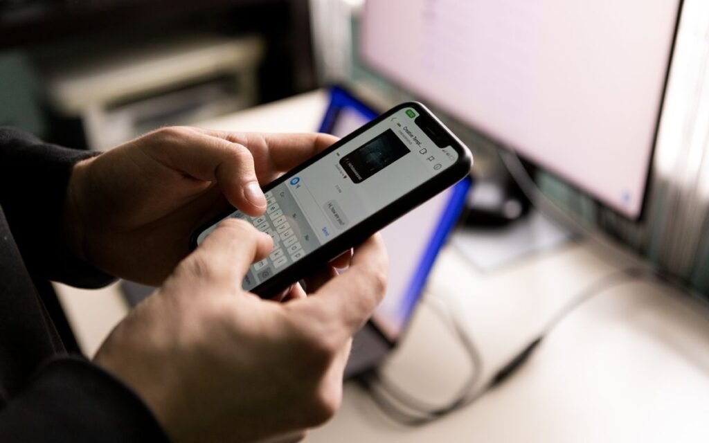 Person typing a chat message on a smartphone at a desk