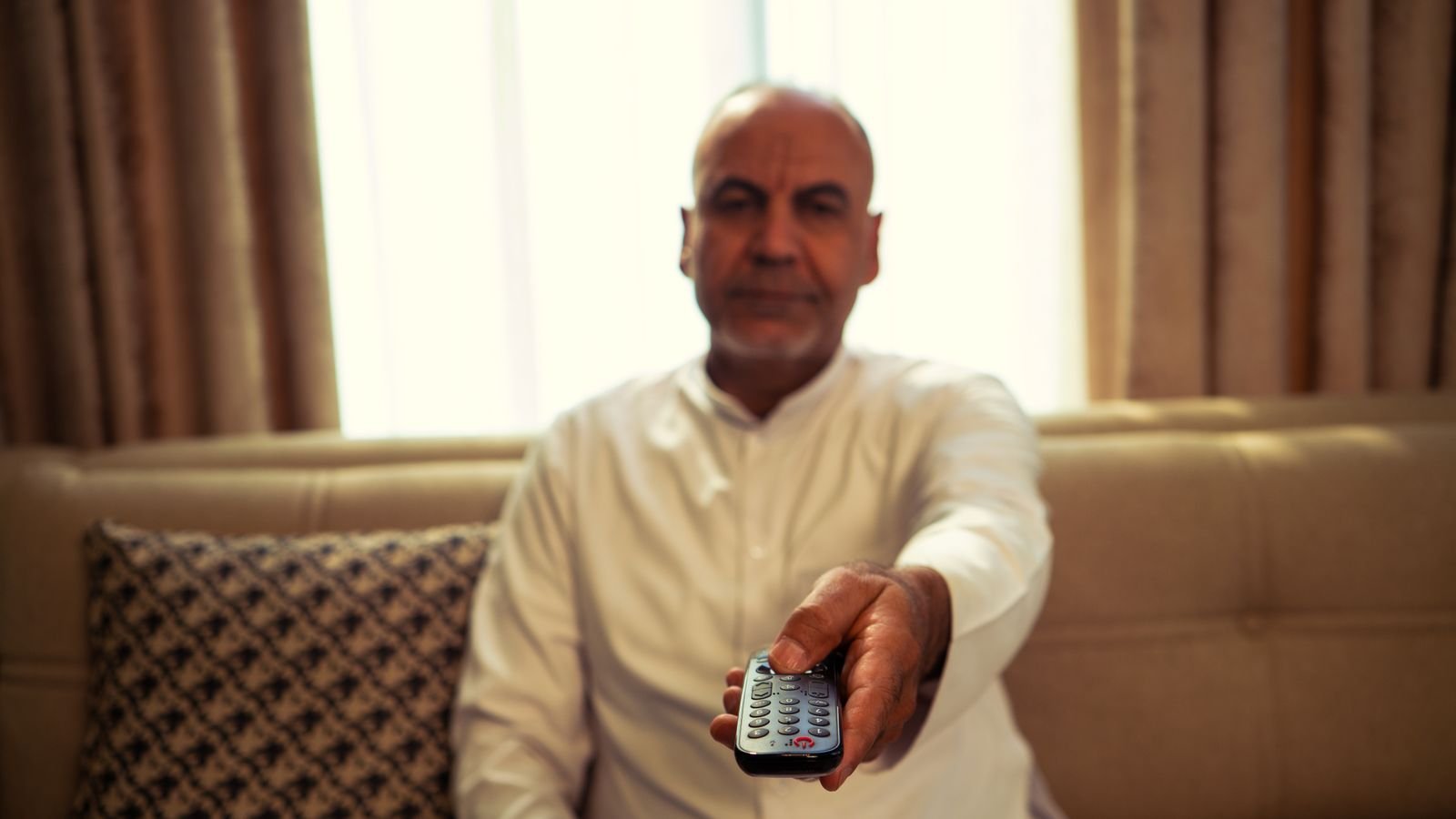 smart tv slow: older man on a sofa pointing a TV remote