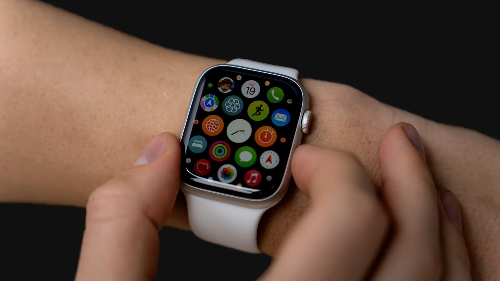 smartwatch hidden features: hand tapping a smartwatch app grid