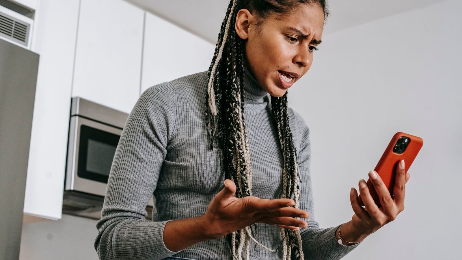 Stop spam calls: frustrated woman in a kitchen staring at her phone