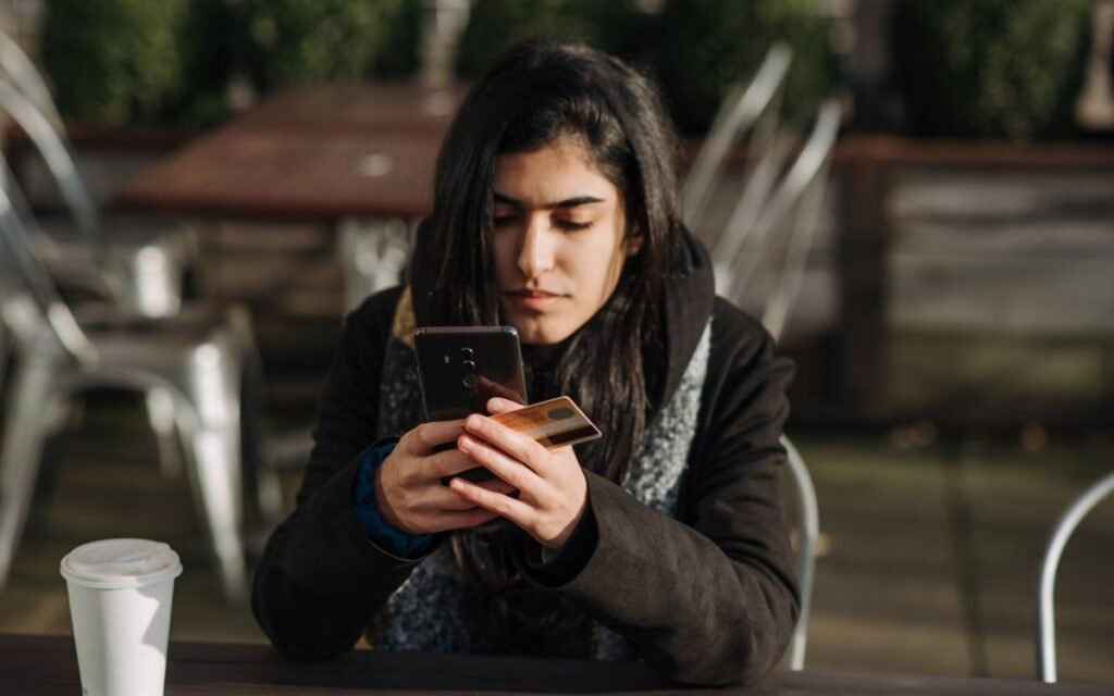 Young woman checking a payment on her smartphone at a cafe table