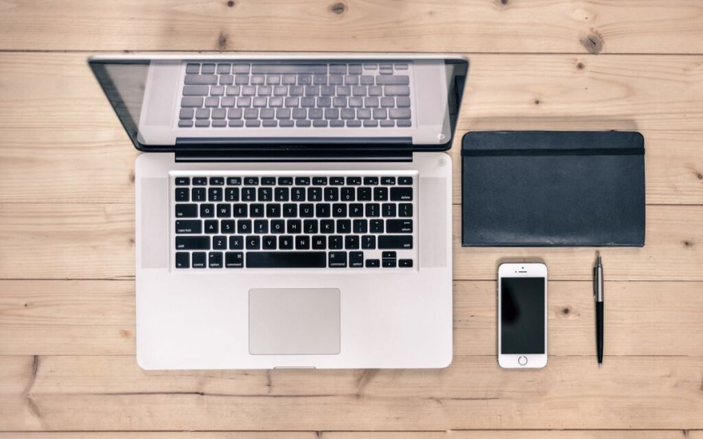 a laptop and phone on a wooden desk